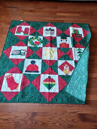 A festive quilt with Christmas-themed patchwork on a wooden floor.