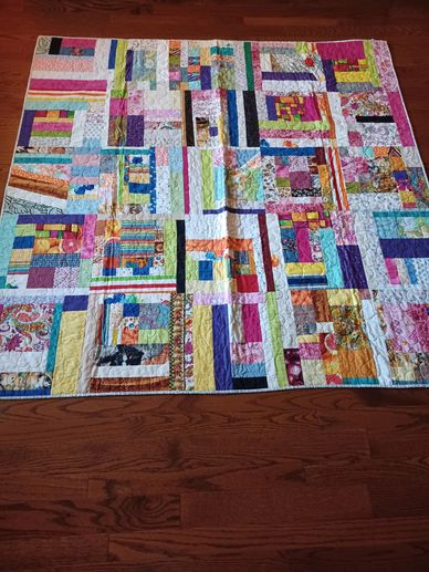 Colorful patchwork quilt with geometric patterns on wooden floor.
