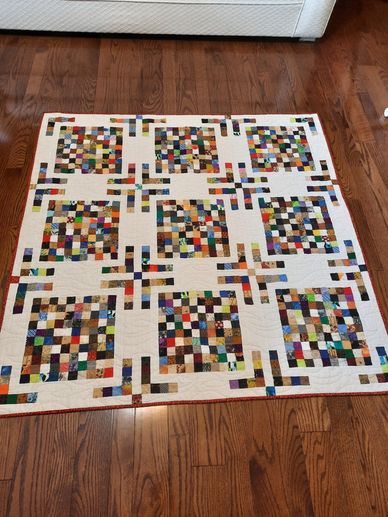 Colorful patchwork quilt with geometric patterns on wooden floor.