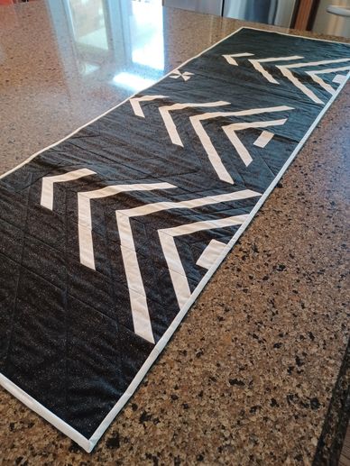 Black and white geometric patterned table runner on a granite countertop.