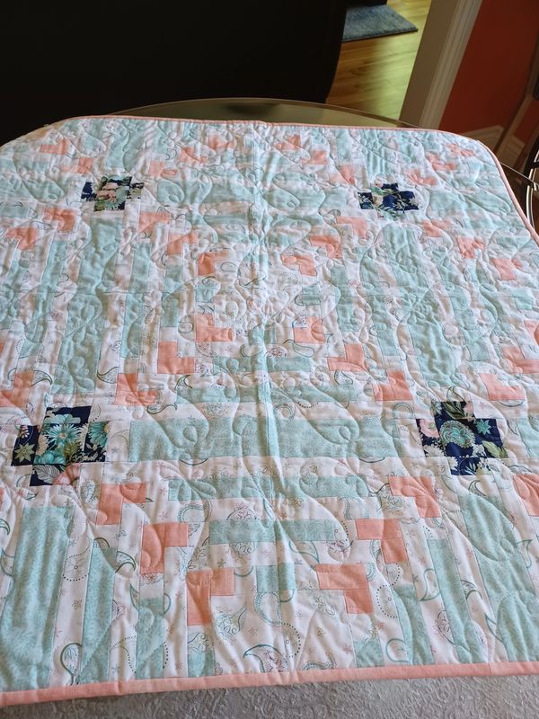 Pastel quilt with floral and geometric patterns.