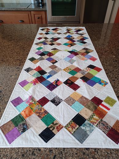 Colorful patchwork quilt table runner on granite countertop.