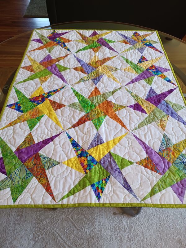Colorful star-patterned quilt with vibrant fabrics and intricate stitching.