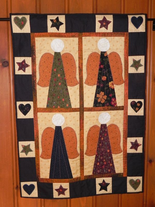 Quilt featuring four patchwork angels with hearts and stars border.
