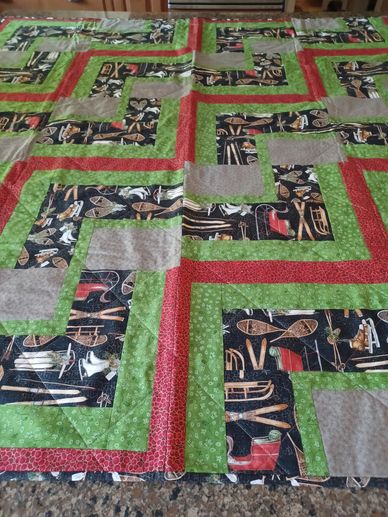 Quilt with green, red, gray, and musical instrument patterned fabric squares.