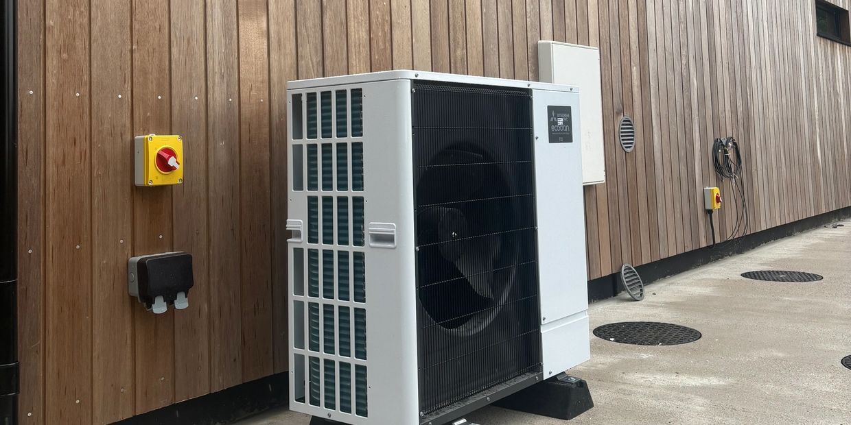 Air source heat pump against a timber clad new build 