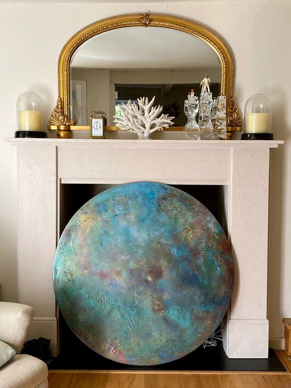 Large abstract resin artwork of the Universe against a fireplace with mirror above.