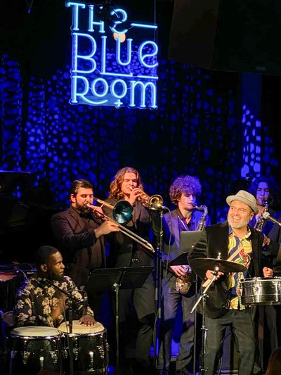 A jazz band playing and singing on teh stage of The Blue Room (neon sign saying The Blue Room in bac