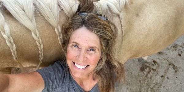 Smiling woman taking a selfie with a braided horse mane.