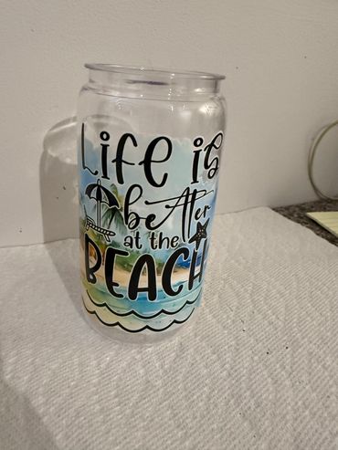 A clear glass with a beach-themed quote and illustrations.