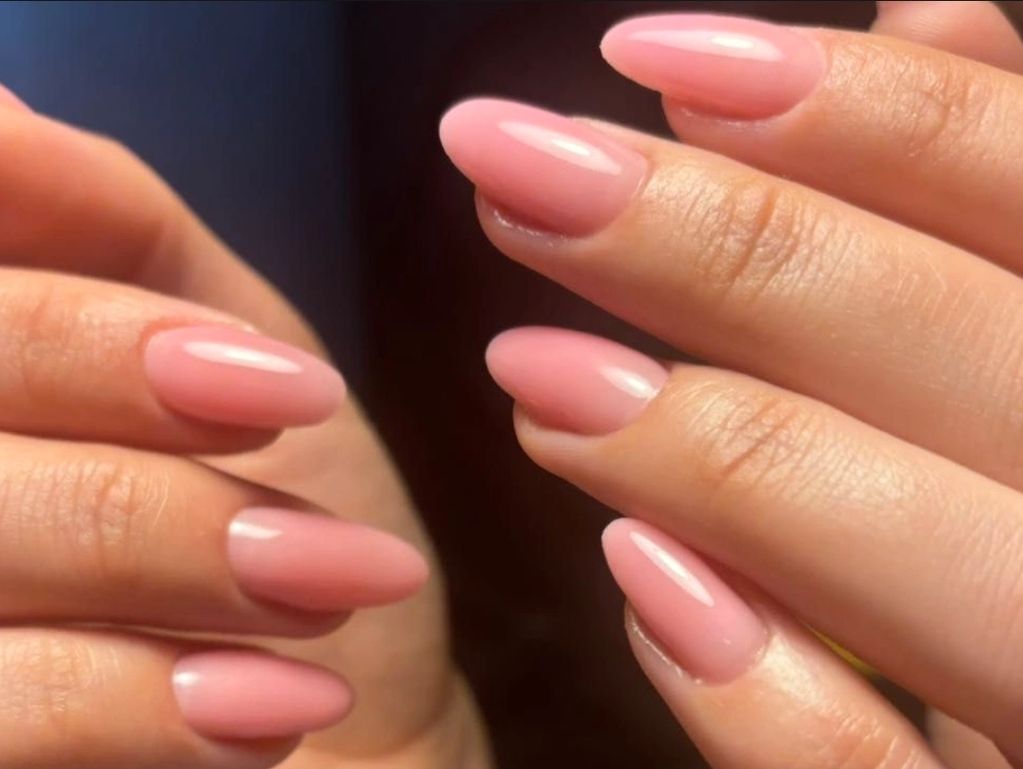 Close-up of glossy, almond-shaped pink manicured nails.