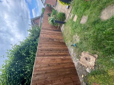 Newly installed wooden fence along a garden path under a cloudy sky.