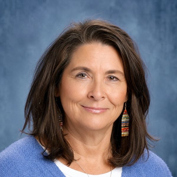 Smiling middle-aged woman with colorful earrings.