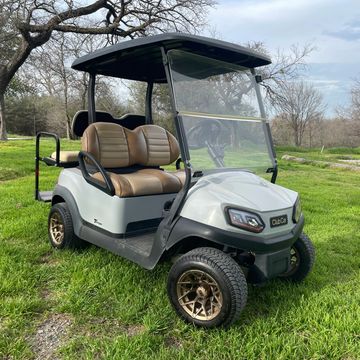 A 2020 Club Car tempo with lights, bronze wheels, brown seats, and a back flip seat.