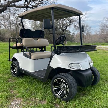 A white 2010 EZGO RXV with a clay basket, 12in wheels and a rear flip seat.
