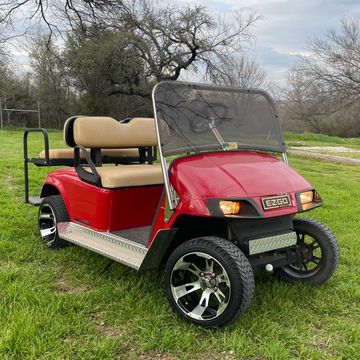 A red 2008 EZGO TXT with a sport windshield, 12in wheels, a factory style light kit, and a rear flip