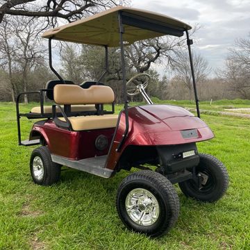 A Maroon 2006 EZGO TXT with a lift kit and rear flip seat.