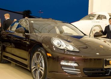 Sleek brown luxury sports car displayed indoors at night.