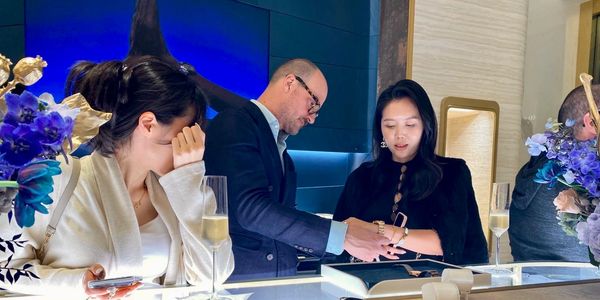 Two women and a man engaged in a discussion, with drinks and flowers on the table.