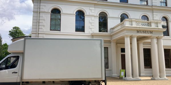 A white truck parked outside a classical museum building with columns.