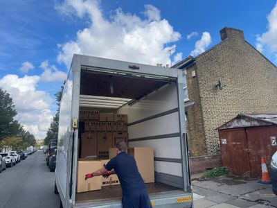 A man loading boxes into a moving truck on a sunny day.