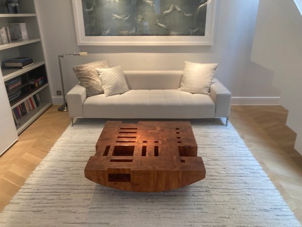 Modern living room with white sofa and artistic wooden coffee table.