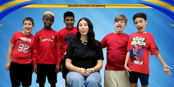A teacher with five kids posing playfully in red shirts at Modderfontein Academy.