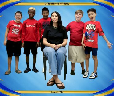 Teacher with five enthusiastic students posing for a school photo.