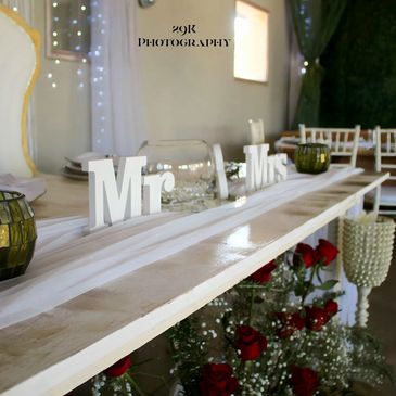 Elegant wedding table setup with Mr and Mrs signs and red roses.