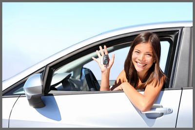 Smiling woman holding car keys from the driver's seat of a car.