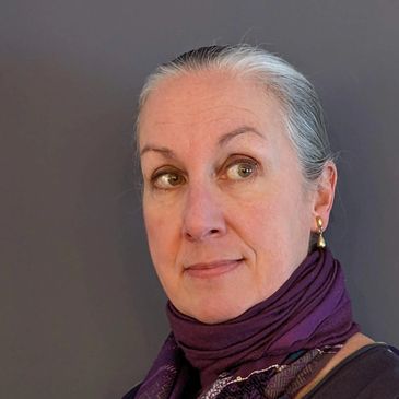 Portrait of a thoughtful older woman with gray hair and a purple scarf looking sideways.