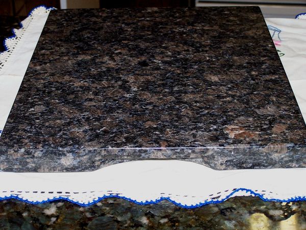 Polished granite slab on a white cloth with blue embroidery.