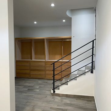 Modern staircase with black railing and wooden storage drawers beneath.