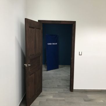 Open wooden door revealing a blue screen with 'CASA SALUD' text inside a room.