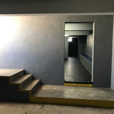 Minimalist stairway leading to a dimly lit hallway with a bench.