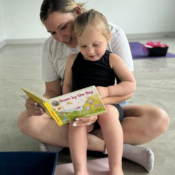 A woman and child joyfully read a book titled 'Down by the Bay' together.