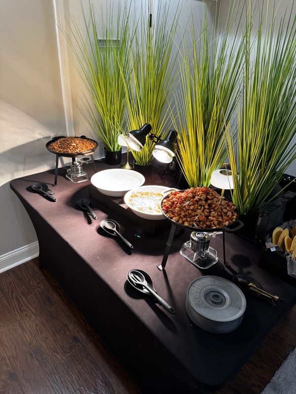 Buffet table with nuts, dips, and serving utensils.