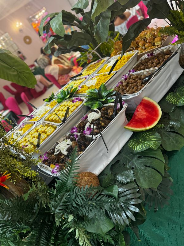Buffet table with diverse dishes and tropical decorations.