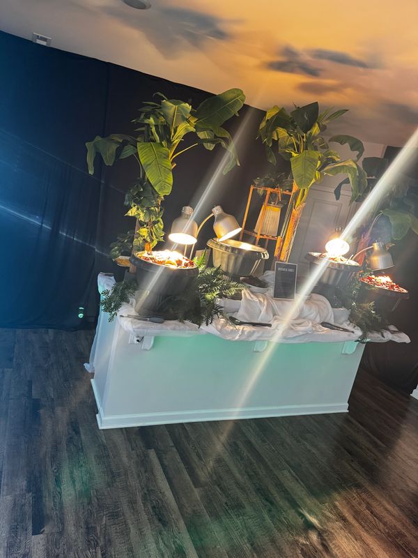 Buffet setup with plants and heating lamps.