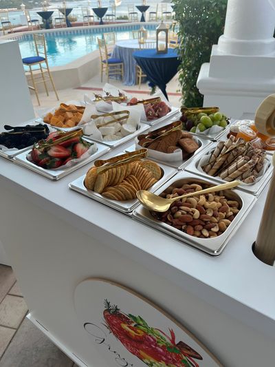 Assorted snacks and nuts displayed on a white counter near a pool.