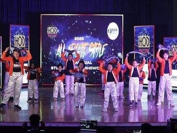 A group of children performing a dance on stage at the 2025 All Urban Style Annual Student Showcase.
