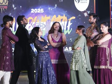 Group of young adults in traditional attire posing confidently on stage with crossed arms.