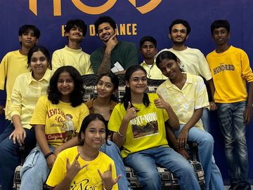 Group of young people in yellow shirts posing in front of a blue wall with HOD logo.