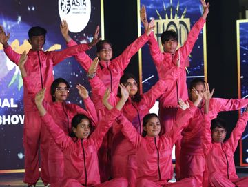 Group of young dancers in pink outfits performing on stage at a dance show.