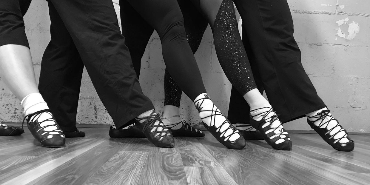 Five Irish dancers pointing their foot. 