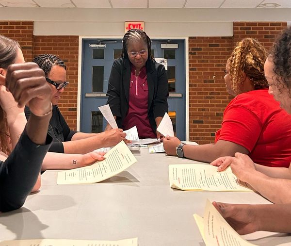 A group discussion with a woman leading and others reviewing documents.