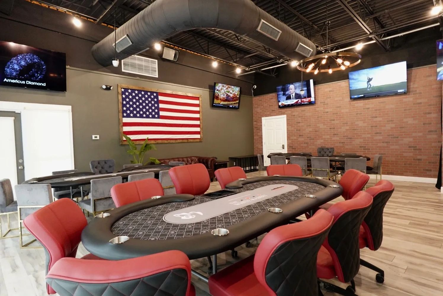Modern poker room with red chairs and multiple TVs on walls.