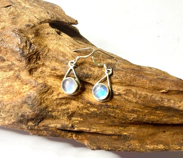 Silver earrings with iridescent gemstones on wood.