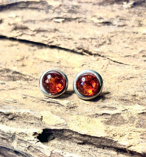 Pair of amber stud earrings on rustic wood.