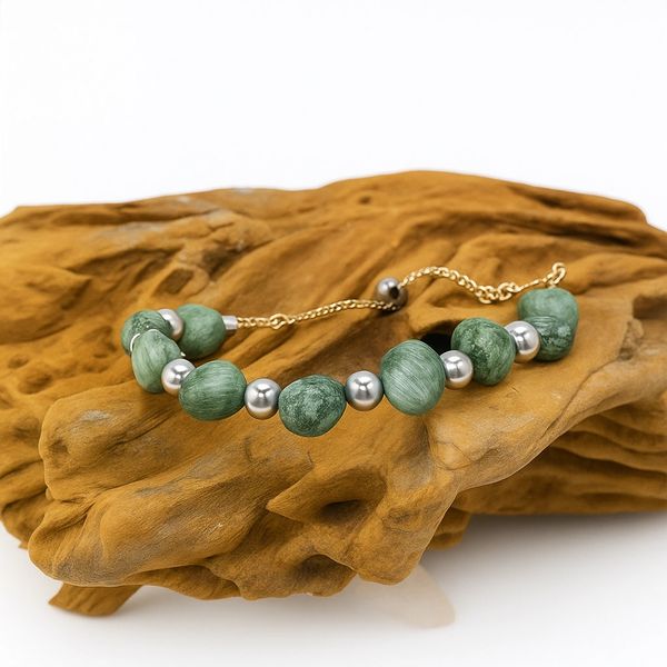 Green stone and silver bead bracelet on wood.